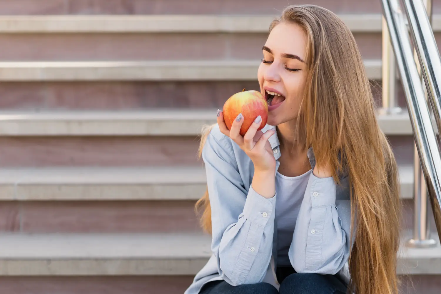 Chica joven comiendo una manzana con los dientes